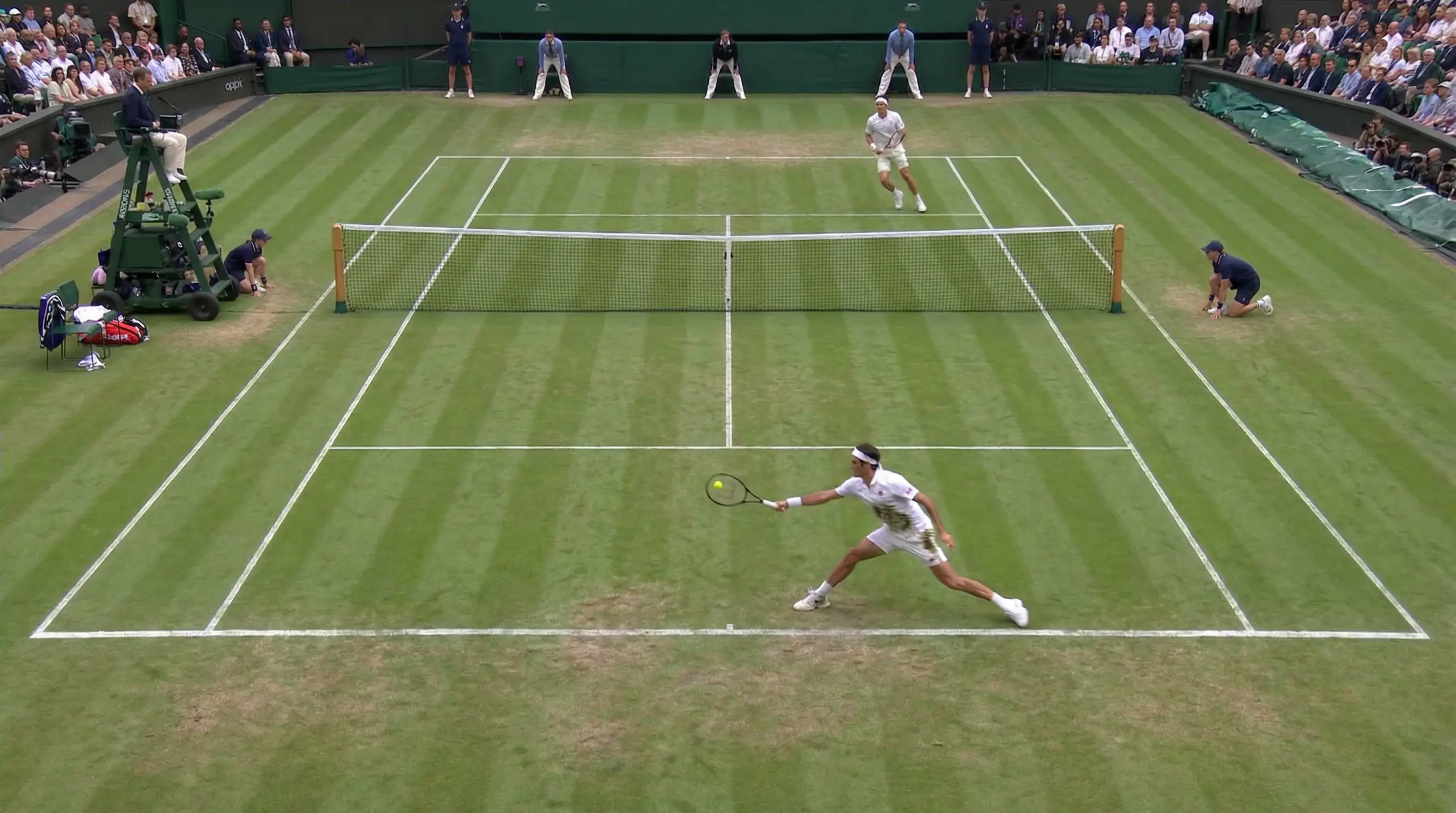 Dos tenistas en un rally largo sobre pista de hierba durante un partido igualado de tenis