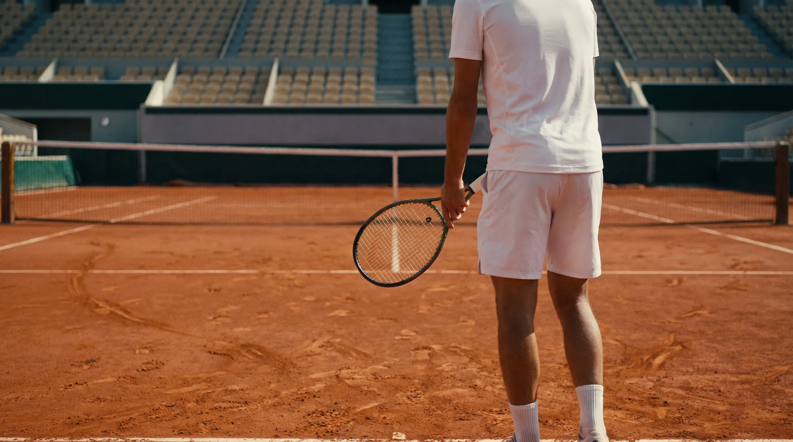 Tenista profesional solo en la pista de tierra batida durante un partido de tenis